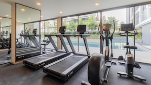 Ett gym med löpband, crosstrainers och utsikt över poolen.