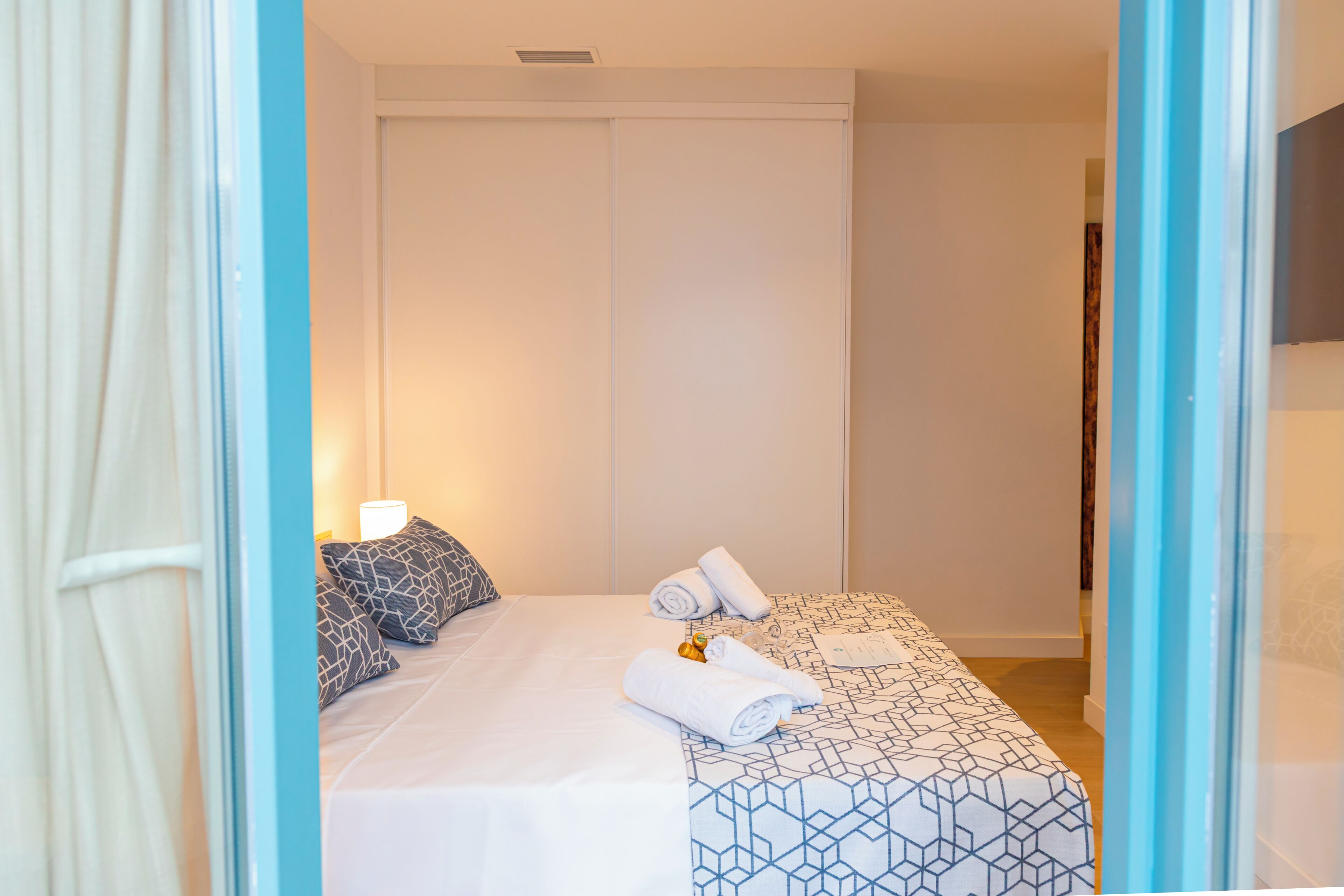 Habitación de hotel con cama, almohadas, una toalla enrollada y un pequeño adorno.