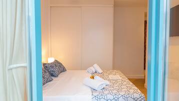 Habitación de hotel con cama, almohadas, una toalla enrollada y un pequeño adorno.