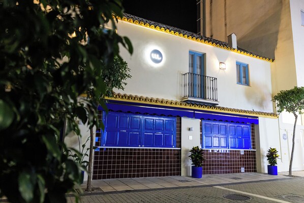 A building with two garage doors, a balcony, and a small light fixture. - Apartamentos Las Olas del Mar (Estepona)