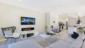 Ein modernes Wohnzimmer mit Kamin, einer Couch, einem Couchtisch und einem an der Wand befestigten Fernseher.
