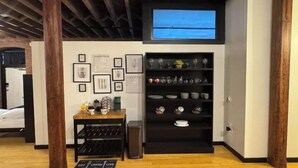A room with a wooden ceiling, a wine rack, a black shelf with dishes, and framed pictures on the wall. - Brick City Loft (Newark)