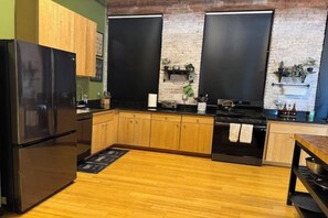 Une cuisine avec des meubles de rangement en bois, un réfrigérateur noir, une cuisinière et un évier.