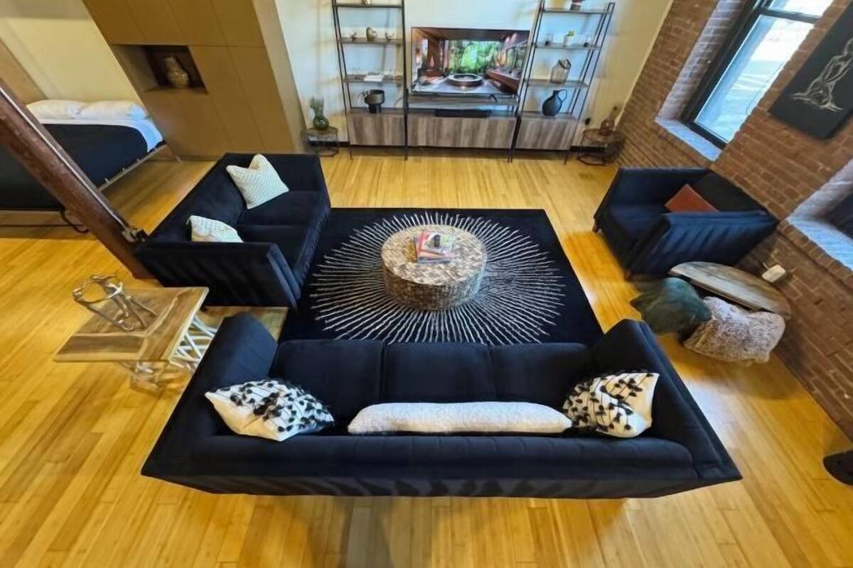 A modern living room with a central coffee table, sofas, and a fireplace.