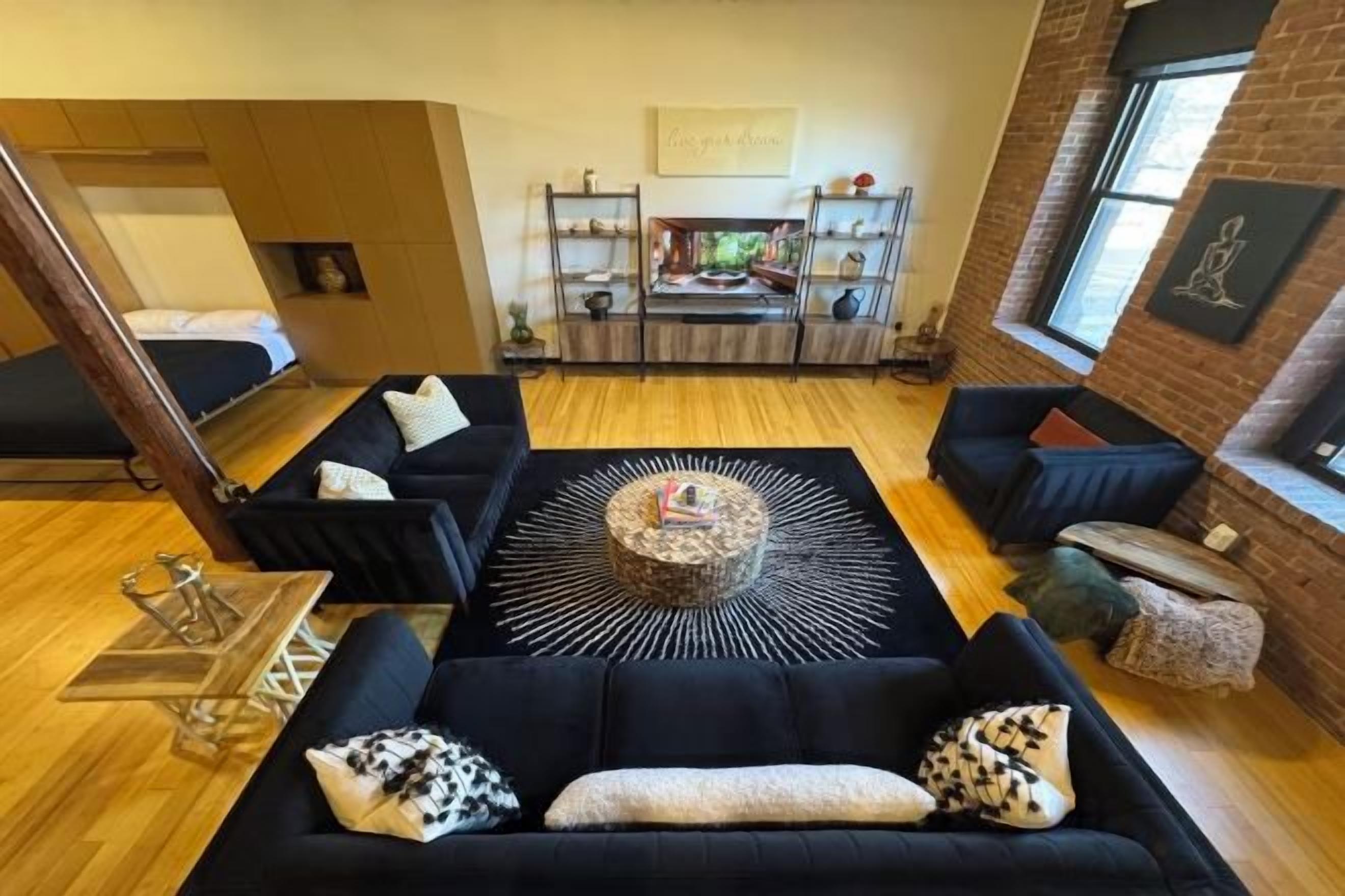 Una sala moderna con un sofá negro, una mesa de centro y una chimenea.