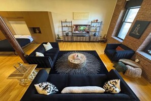 A modern living room with a black sofa, a coffee table, and a fireplace. - Brick City Loft (Newark)