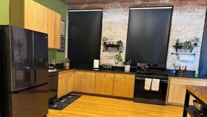 A modern kitchen with wooden cabinets, a black refrigerator, a stove, and a microwave. - Brick City Loft (Newark)