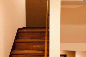 Eine Holztreppe mit Handlauf, die zu einer Zwischenebene führt.