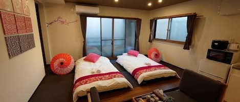 A room with two beds, a dining table, and a view of the sea.