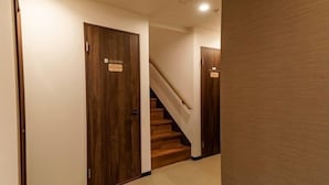 A hallway with wooden doors labeled "Laundry" and a staircase leading to another floor. - OHAYO・Oshiage (Tokyo)