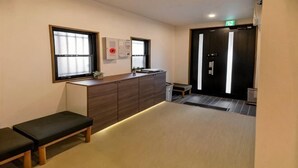 A room with a bench, a counter with a sink, and a door with an exit sign. - OHAYO・Oshiage (Tokyo)