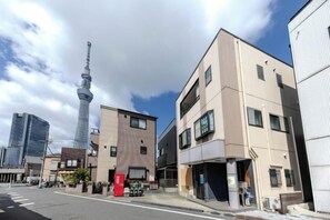 Ein mehrgeschossiges Gebäude mit flacher Fassade, einem sichtbaren Eingang und einem Parkplatz davor.