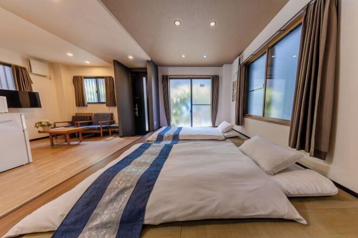 A hotel room with two beds, a desk, and a television.