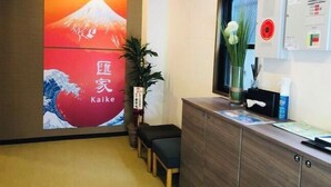 A reception area with a large poster of Mount Fuji, a wooden reception desk, a potted plant, and a bulletin board with notices. - OHAYO・Oshiage (Tokyo)