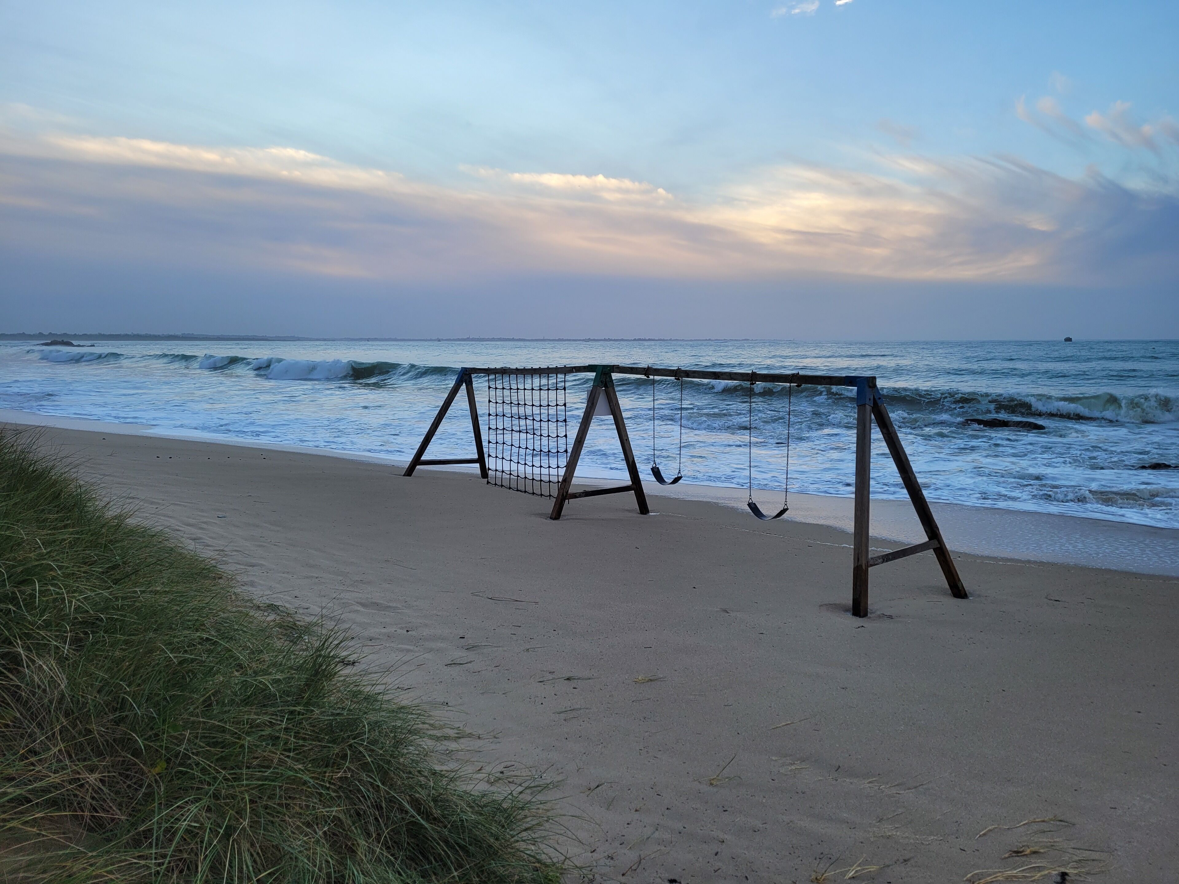 A beach with a soccer goal and swings.