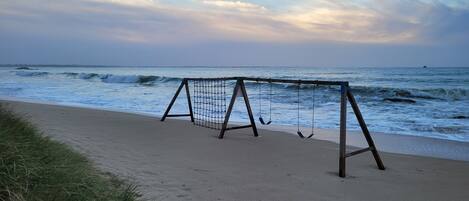 A beach with a soccer goal and swings.