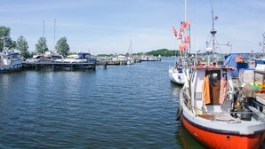 Uma marina com vários barcos atracados, incluindo um barco vermelho em destaque no primeiro plano.