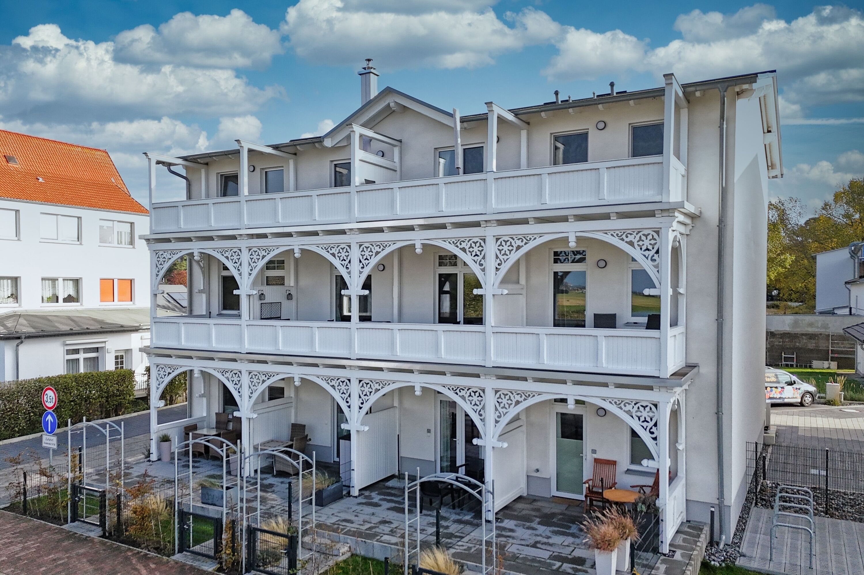 A multi-story building with a white exterior and a balcony on the upper floor.
