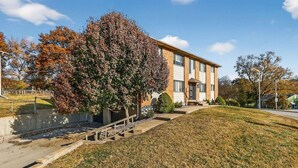A two-story building with a brick facade, a front entrance with a door, and a small set of stairs leading up to the entrance. - King Bed 2BR Retreat, Private Garage (Kansas City)