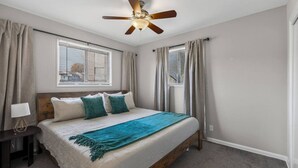 A bedroom with a bed, curtains, a ceiling fan, and a window with blinds. - King Bed 2BR Retreat, Private Garage (Kansas City)