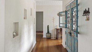 A hallway with a wooden floor, a blue door with decorative metalwork, and a cactus plant. - Saltwood: Yallingup Garden Sanctuary by the Sea (Yallingup)