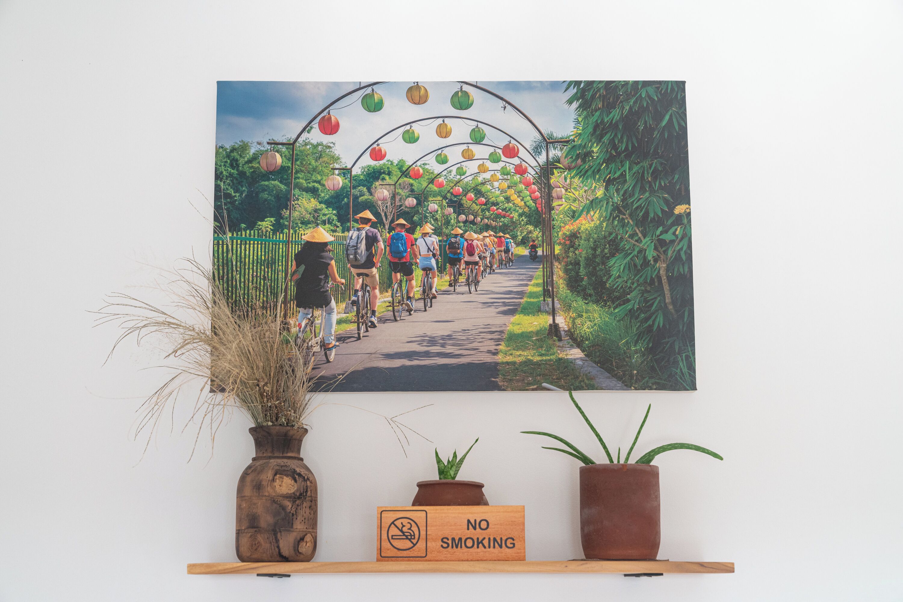 A wall-mounted painting of a pathway lined with lanterns and people, with a 'No Smoking' sign below.