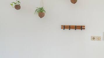 A wall-mounted branch with three hanging planters.