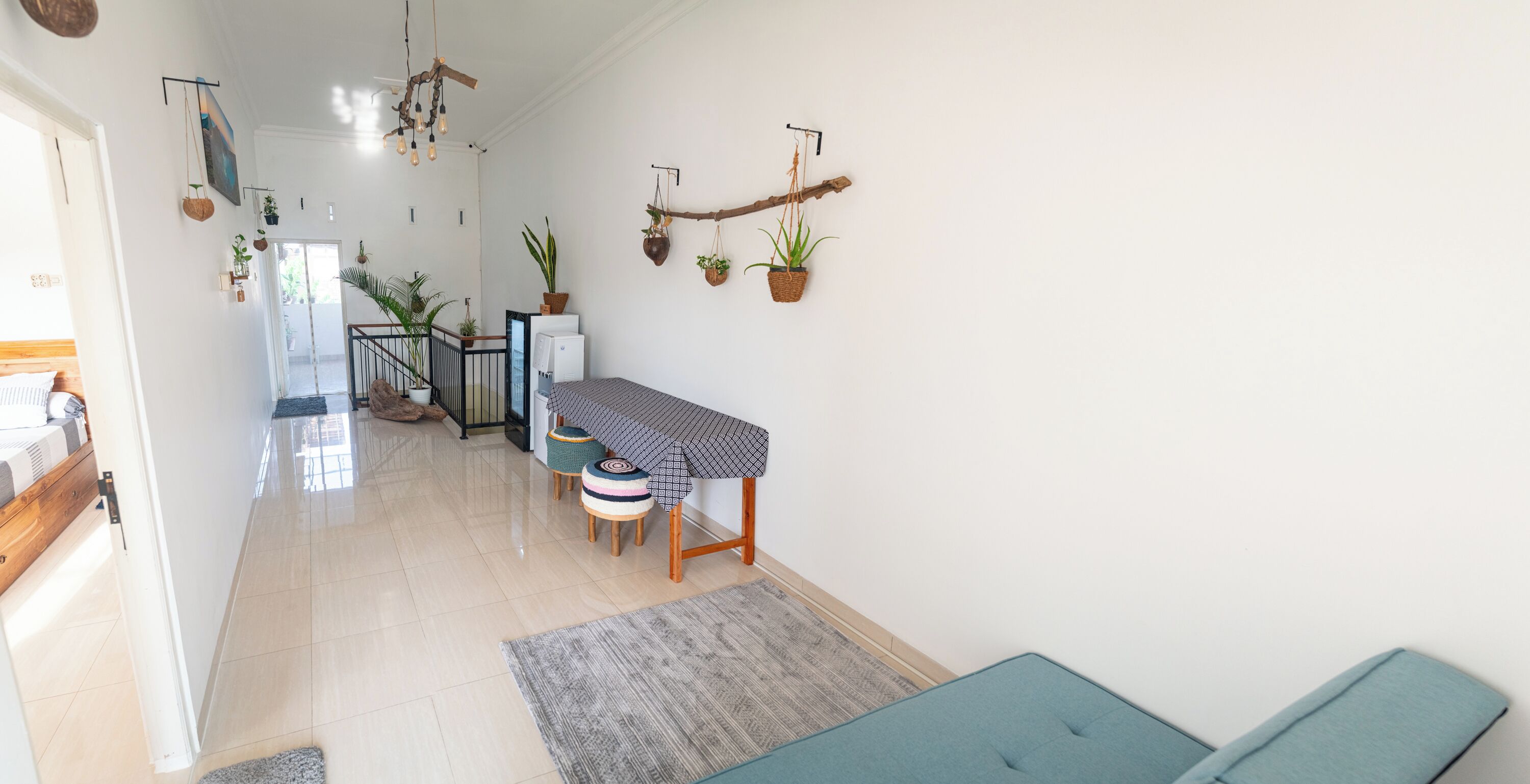 A modern living room with a sofa, a dining table with chairs, and a kitchen area with a refrigerator and a microwave.