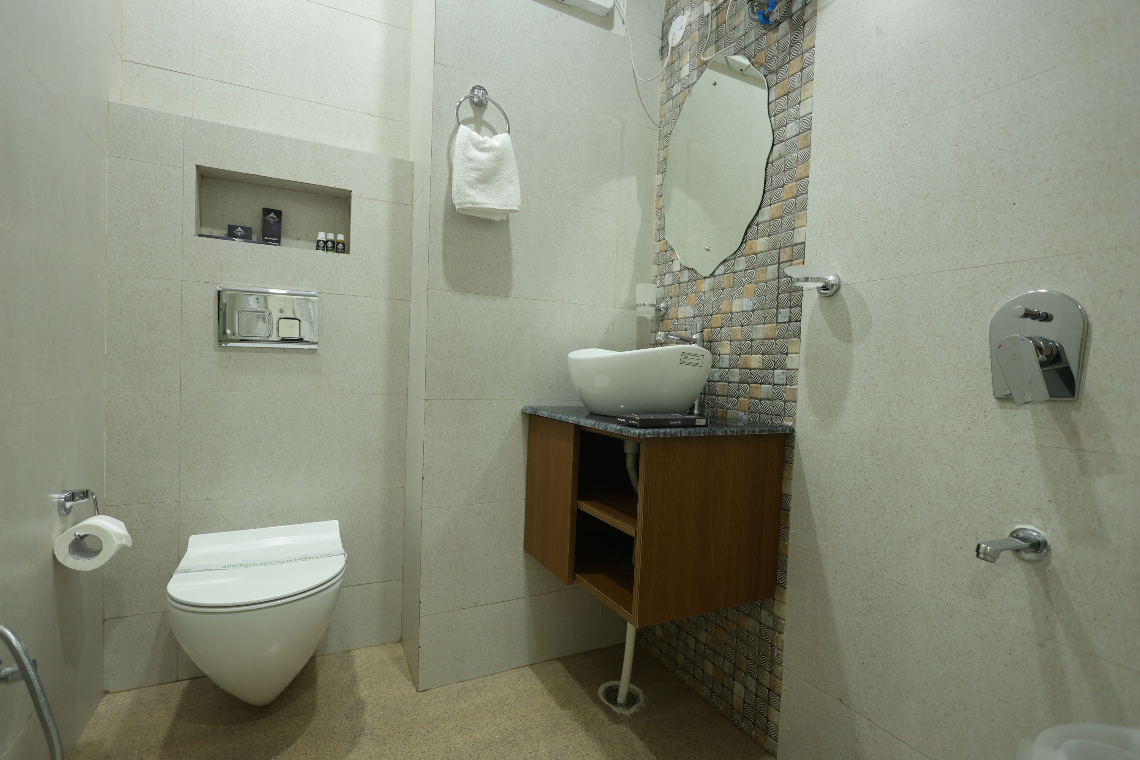 A bathroom with a toilet, a sink with a mirror, a towel rack, and a shelf with toiletries.