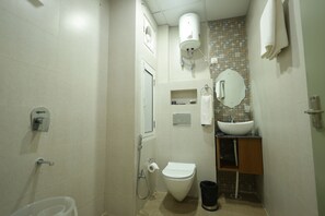 Een kleine badkamer met toilet, wastafel en douche.