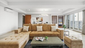 A modern living room with a sectional sofa, a coffee table, and a view of the balcony. - Fenja by Kozystay - Senayan (Jakarta)