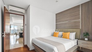 A modern bedroom with a bed, wooden floor, and a view of a dining area. - Fenja by Kozystay - Senayan (Jakarta)