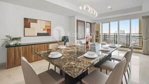 A modern dining area with a marble table, chairs, and a city view through large windows. - Fenja by Kozystay - Senayan (Jakarta)