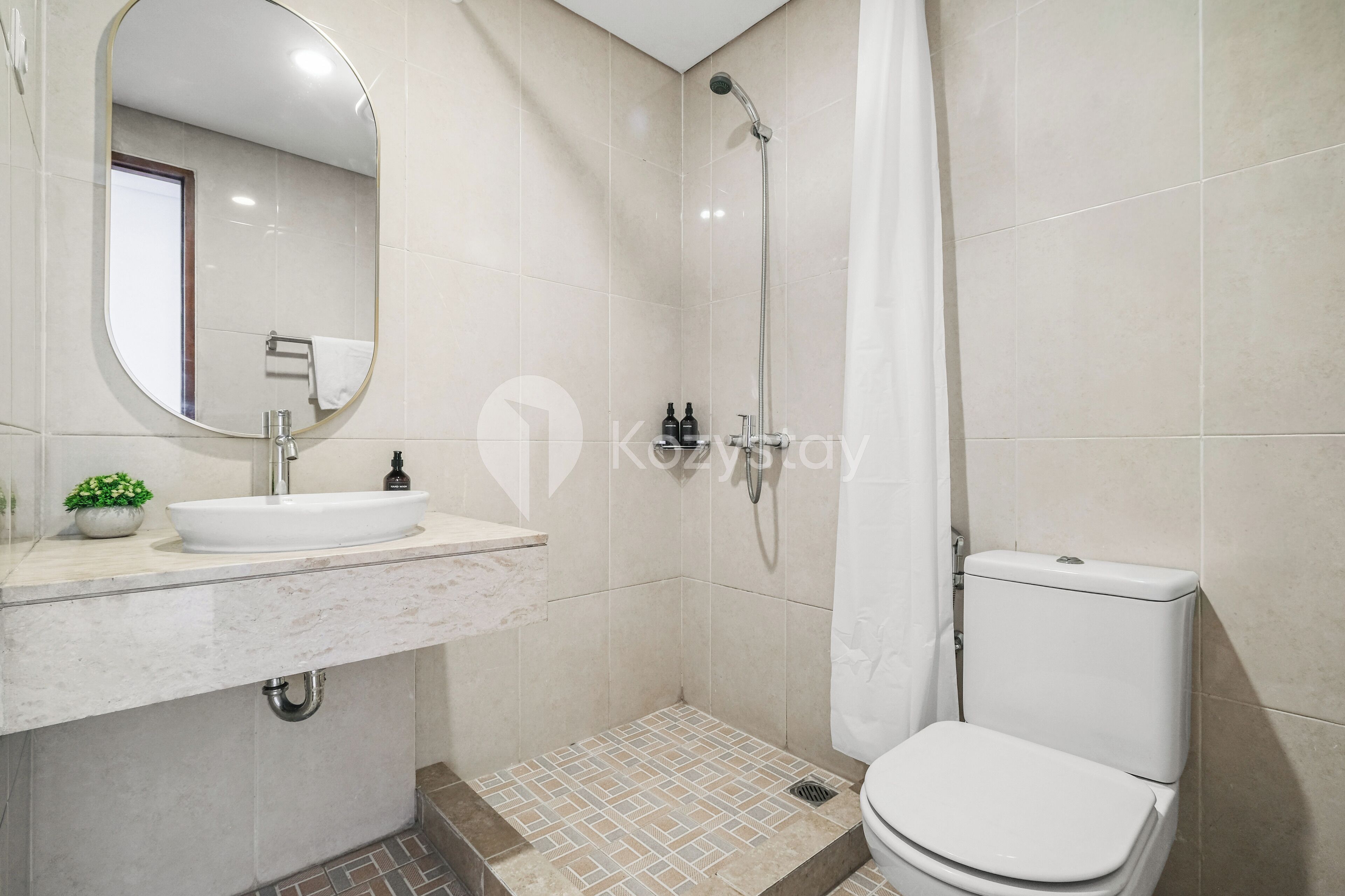 Une salle de bain équipée d’un lavabo, d’un miroir, d’une douche et de toilettes.