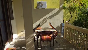 Un espacio al aire libre cubierto con una mesa, sillas, un banco y una barandilla.