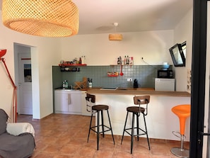 Une cuisine dotée d’un plan de travail en bois, de deux tabourets de bar, d’un luminaire suspendu et d’un four à micro-ondes.