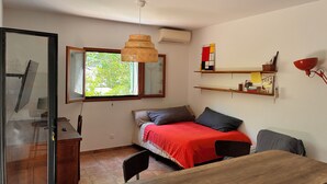 A room with a bed, a desk, a chair, a hanging lamp, a shelf with books, and a window with a view of greenery. - Summer rental Ajaccio (Ajaccio)