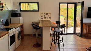 A compact kitchen with a washing machine, a microwave, and a coffee maker. There is a bar area with stools and a view of the outside. - Summer rental Ajaccio (Ajaccio)