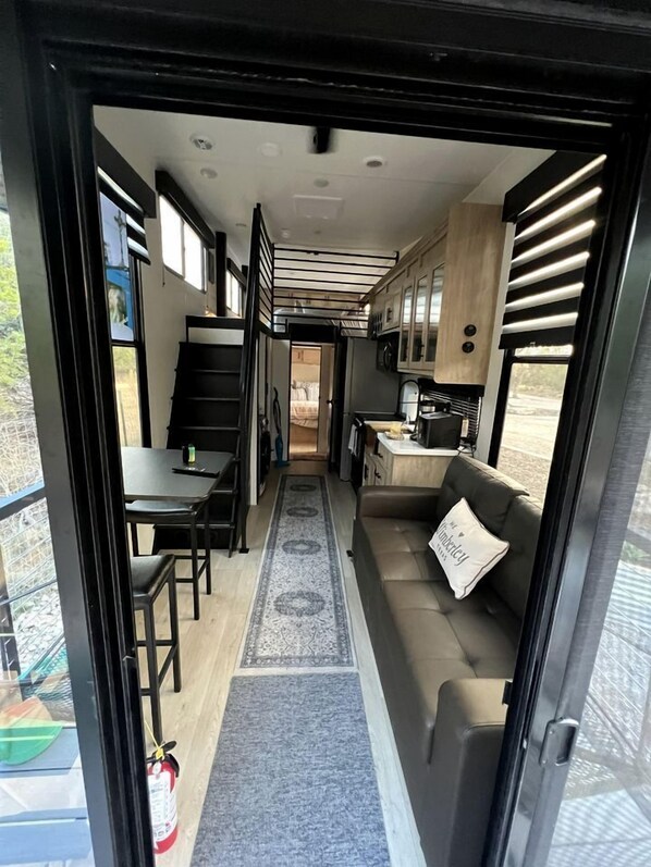 A compact RV interior with a kitchenette, dining area, and seating space. - Luxurious Boutique Tiny House for a Relaxing Getaway in Wimberley, Texas (Wimberley)