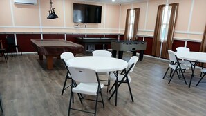 Une pièce équipée d’une table de billard, d’un baby-foot et d’un téléviseur à écran plat fixé au mur.