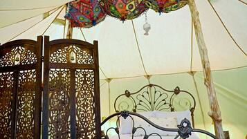 A tent with a bed, decorative curtains, and a hanging bell.