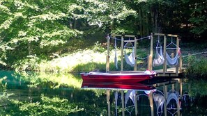 Ein rotes Boot liegt an einem hölzernen Steg festgemacht, mit Hängematten.