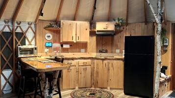 Una cucina compatta con mobili in legno, un frigorifero nero e un piccolo piano di lavoro.