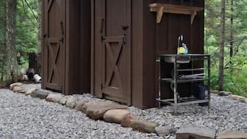 A rustic wooden shed with a slanted roof and a small porch area.