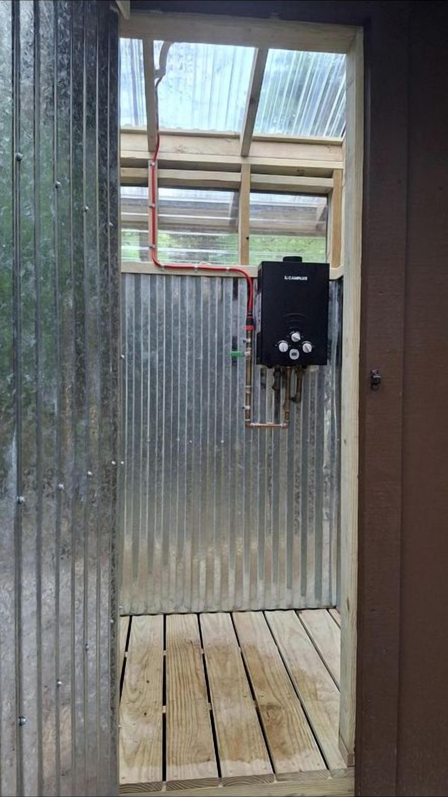 A metal-walled room with a wooden floor, a black electrical box, and a window with a metal frame.