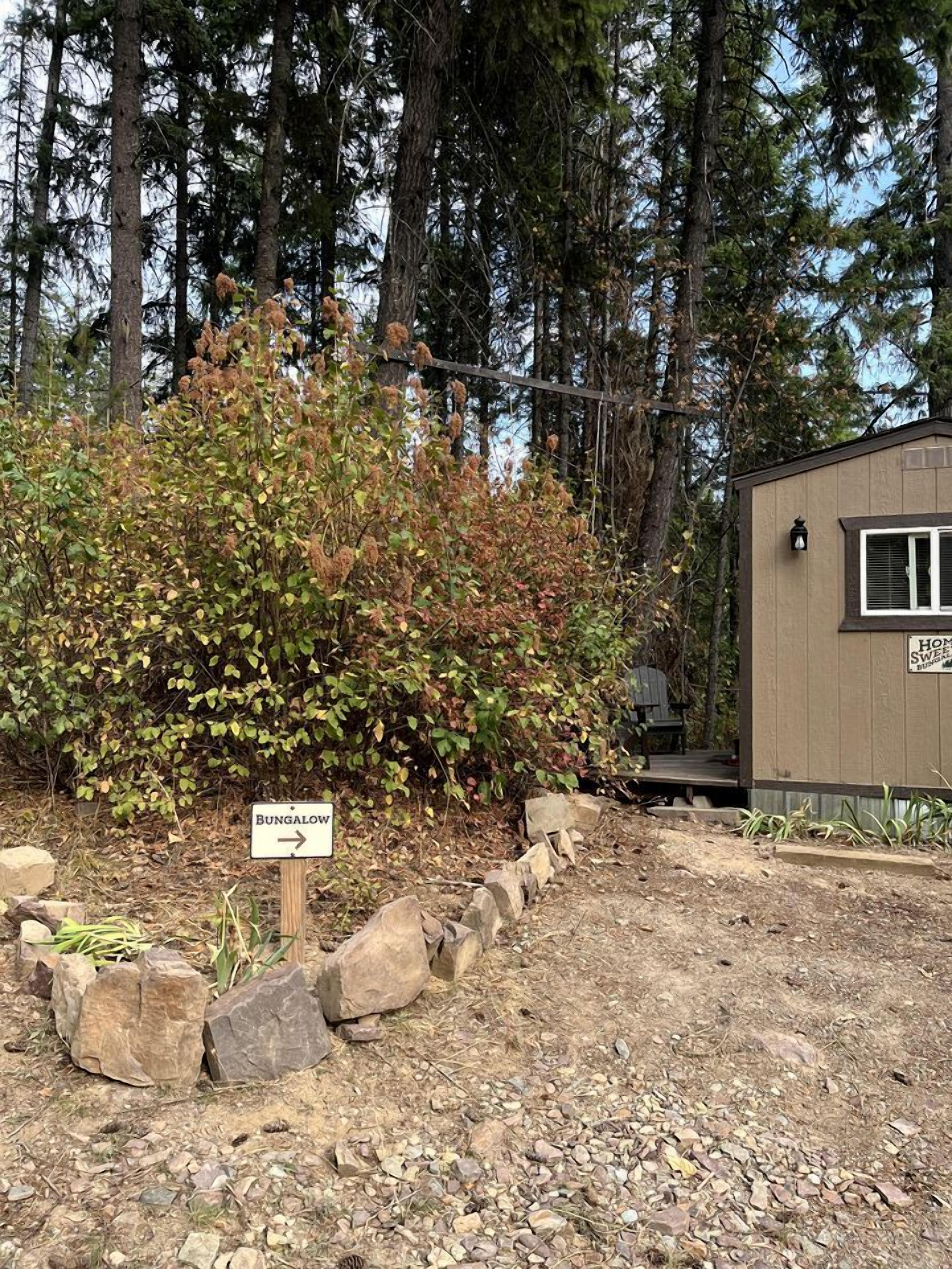 Un petit bâtiment en bois portant l’inscription « Bungalow » et sur lequel est fixé un panneau indiquant la direction à suivre, vers la droite.
