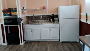 A compact kitchen with white cabinets, a white refrigerator, a coffee maker, and a microwave.