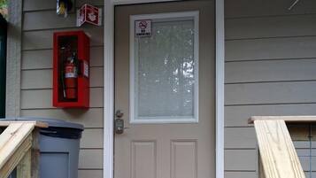 A front door with a 'No Smoking' sign, a fire extinguisher, and a trash can outside.