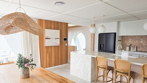 Una cocina moderna con una isla de madera, armarios blancos y un comedor con mesa de madera y sillas de mimbre.