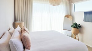 Un dormitorio moderno con una cama grande, techo de madera y un ventanal con cortinas ligeras.